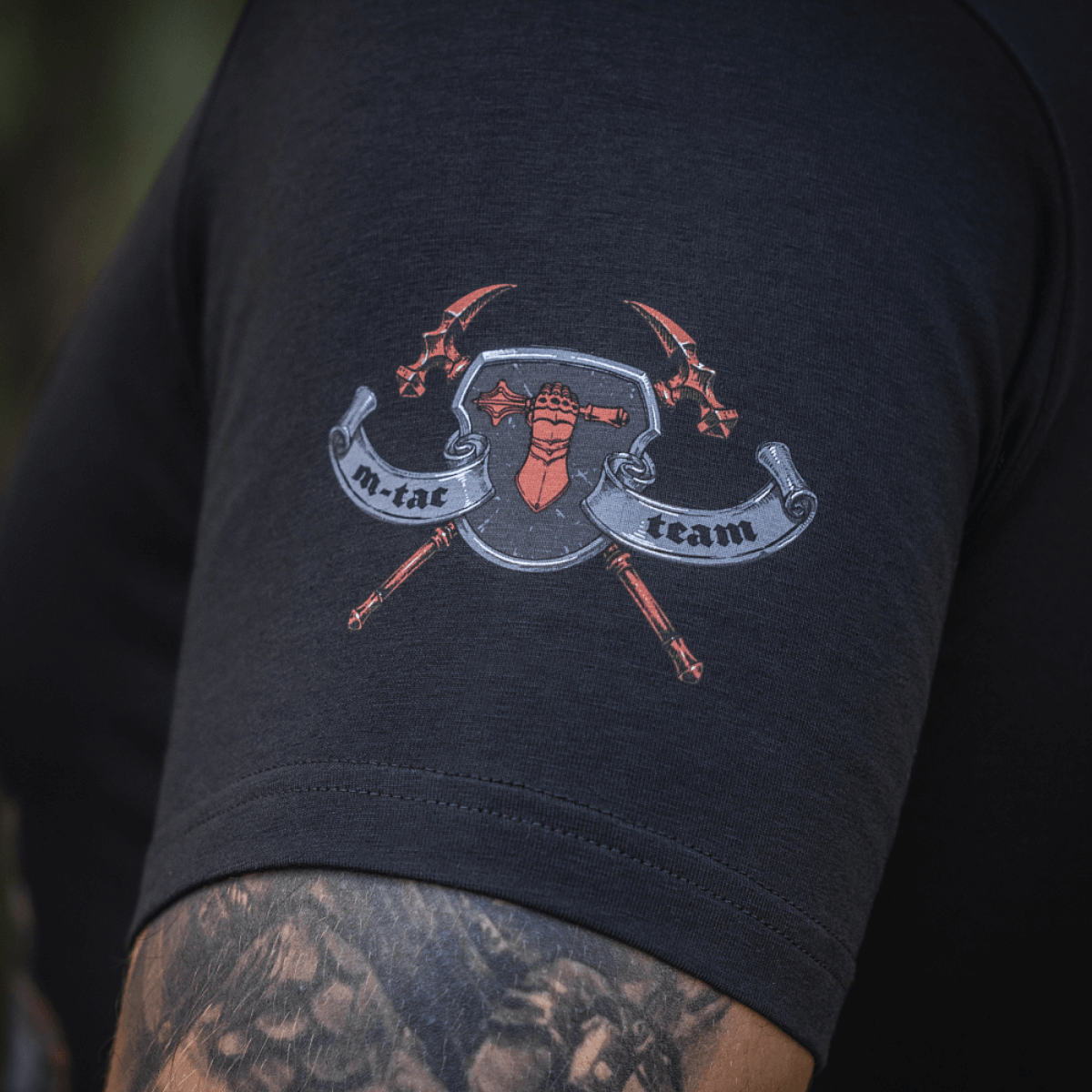 Detalje af M-Tac T-Shirt Steel Knight med logo på ærme, symboliserende styrke og mod hos Ukraines forsvarsstyrker.