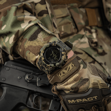 M-Tac Tactical Ur 2037 på en camouflerad hand, visar robust design med LED-bakgrundsbelysning och funktioner för taktisk användning.