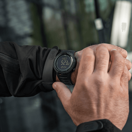 M-Tac Tactical Ur 2147 på handleden i naturen, robust design för utomhus och taktisk användning med kompass och LED-belysning.