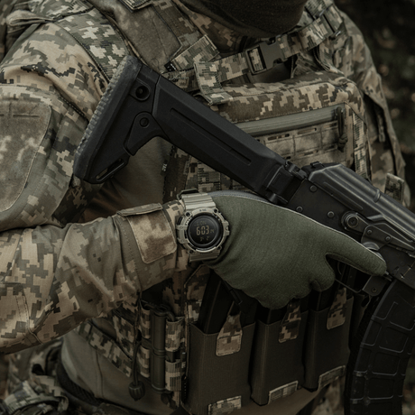 Person i camouflagedräkt bär M-Tac Tactical Ur med Kompas 2233 i en militär miljö.