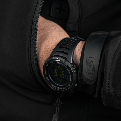 M-Tac Tactical Ur 2147 i handen, visar robust design, hållbarhet och utomhusfunktioner, inklusive kompass och LED-bakgrundsbelysning.