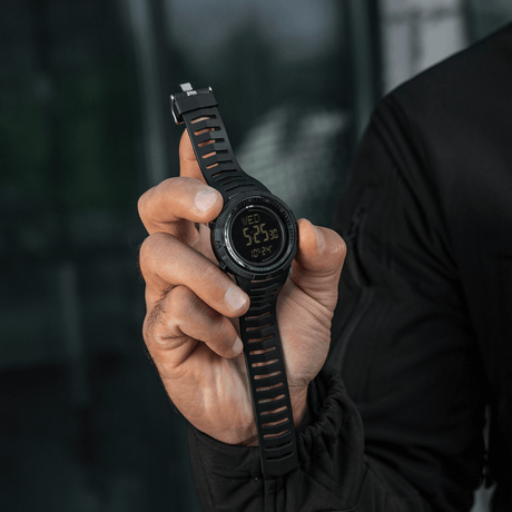 M-Tac Tactical Ur 2147 hålls av person, visar robust design för taktisk eller daglig användning, med funktioner som kompass och LED-ljus.