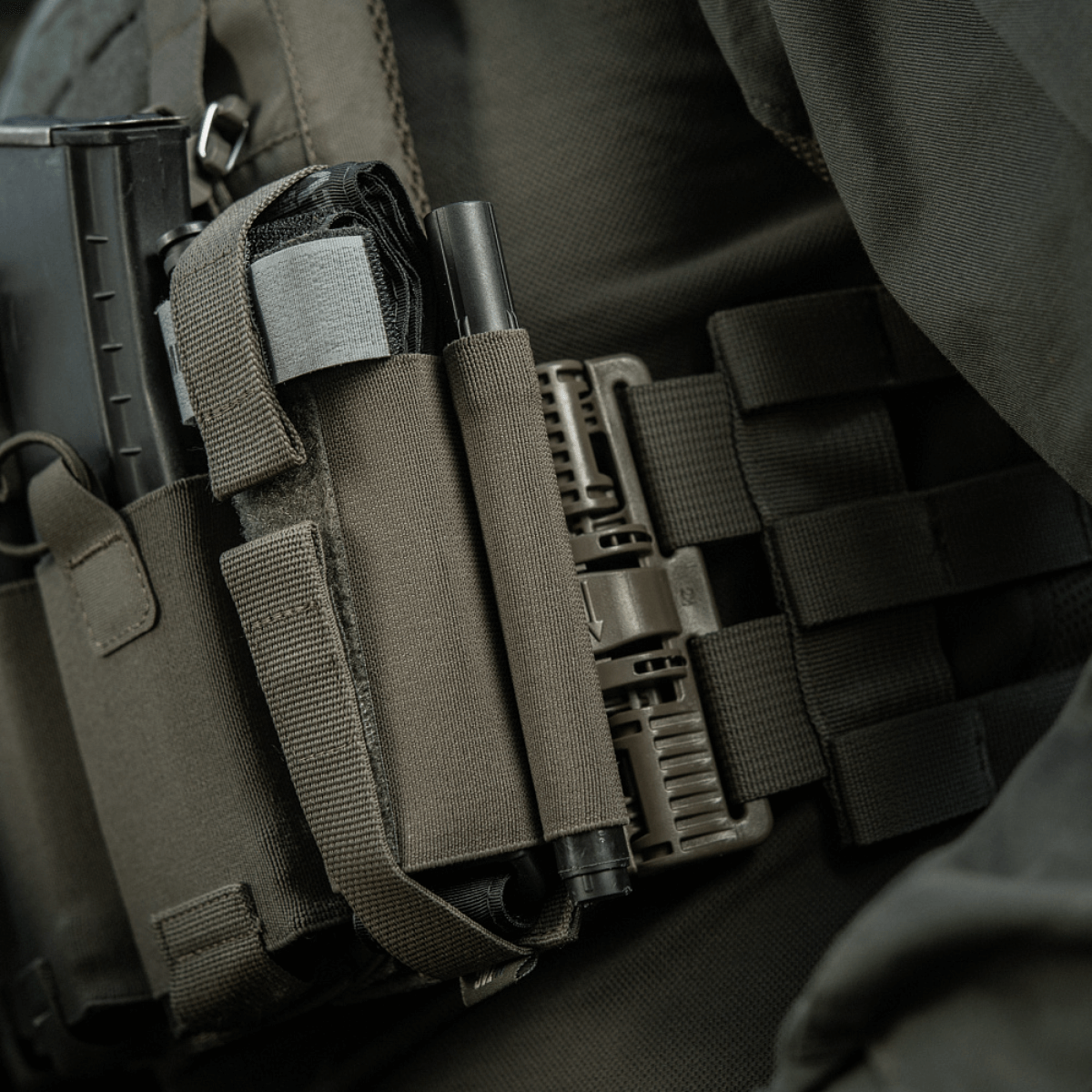 M‑Tac Tourniquet Pouch Elastic Gen.5 monteret på taktisk udstyr med elastisk velcro bånd, praktisk til CAT tourniquet.