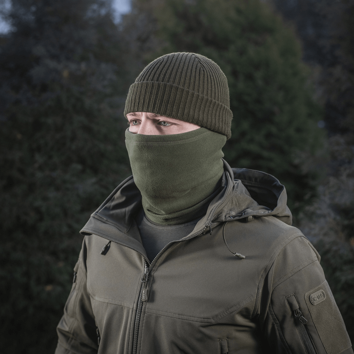 Person iført M-Tac Tube Scarf Polartec i olivenfarve til udendørs aktiviteter om vinteren.