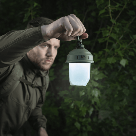 Man håller M-Tac Turist Hänglampa i skogen, idealisk för camping, fiske och jakt med 200 lumen LED-ljus.