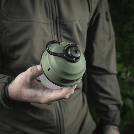 M-Tac Turist Hänglampa i användning, hålls i hand, idealisk för camping och utomhusaktiviteter, med retrodesign och modern LED-teknik.