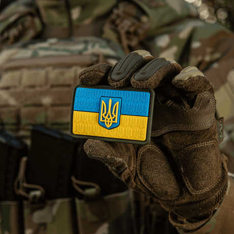 M-Tac Patch Ukraine Flag med vapensköld i PVC med 3D Trident, hålls av en person i militärt camouflagemundering.