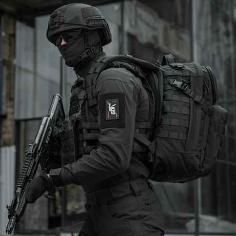 Taktisk operatör bär "M-Tac Patch Bad Boy (Broderi)" med kaninkranium på spader ess-kort, håller vapen, i urban miljö.