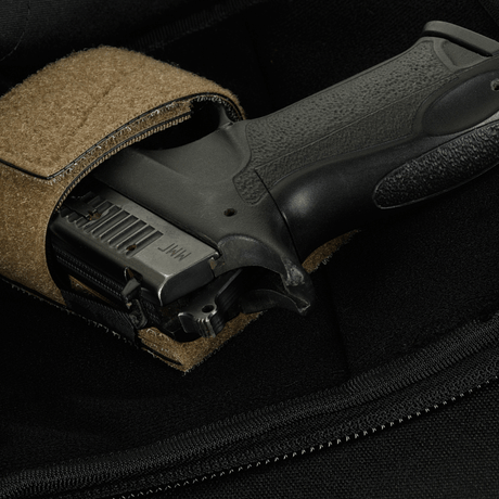 Närbild av en pistol i en M-Tac Sphaera Hardsling Bag Large Elite med Velcro, gjord av robust Cordura-tyg med Velcro-fäste.