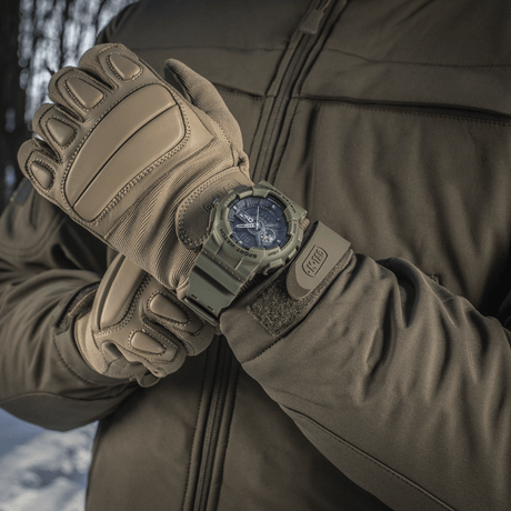 M‑Tac Sportklocka med robust design, perfekt för utomhusaktiviteter, visad på arm med handskar i vinterlandskap.
