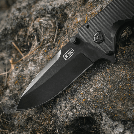 M-Tac Outdoor & Militär fällkniv - Type 7 med blad i svartbelagt rostfritt stål på klippa.