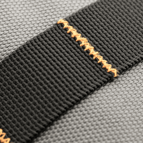 Närbild av M-Tac Urban Line City Patrol väska material: svart axelrem med orange sömmar, 600D polyester, vattenavvisande.