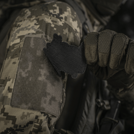 Soldat i kamouflagejacka fäster M‑Tac Patch Baba-Yaga Vertical på ärmen med velcro.