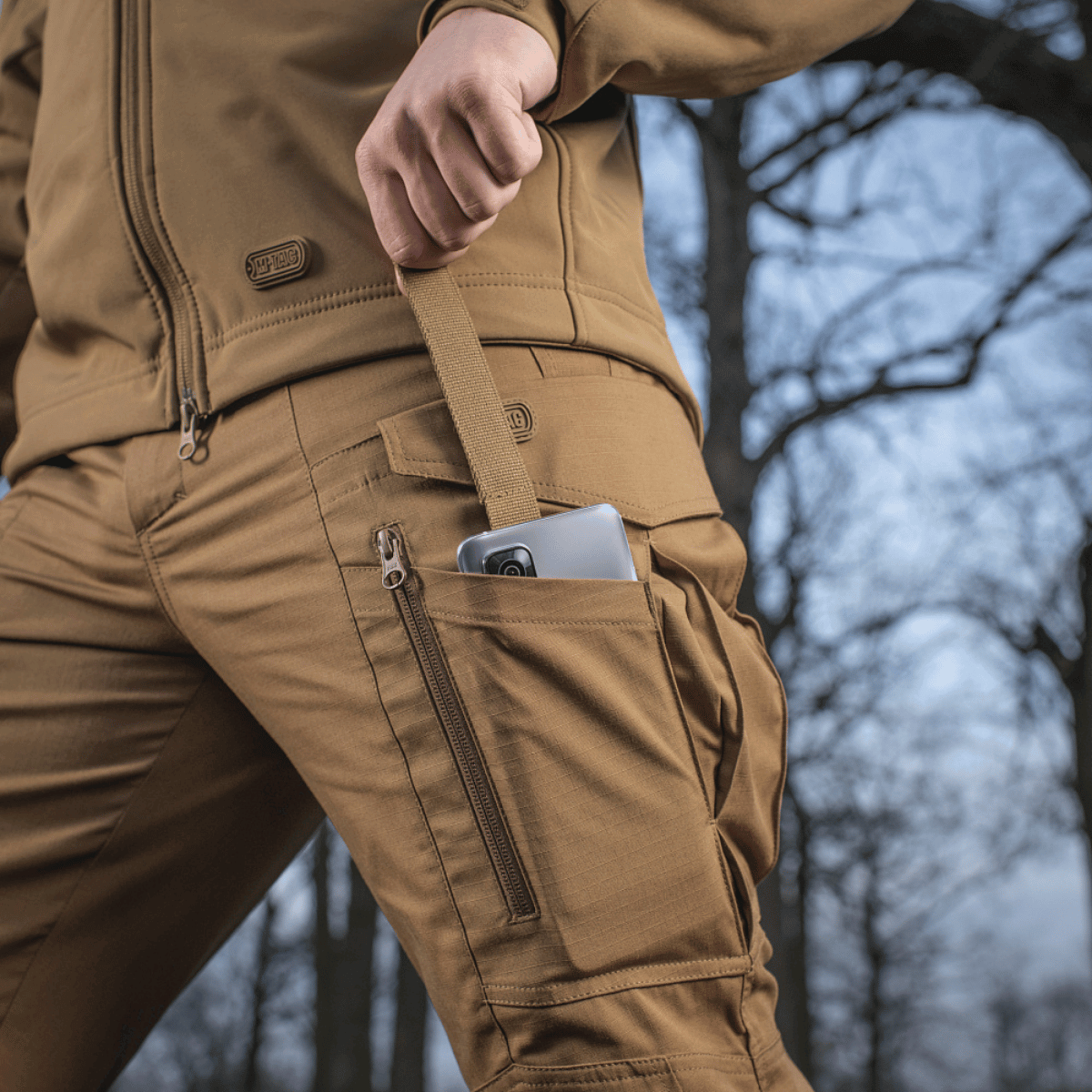 M-tac Taktiske Bukser Conquistador Gen. I Flex med rip-stop materiale til udendørsaktiviteter, viser slidstærke lommer i brug.