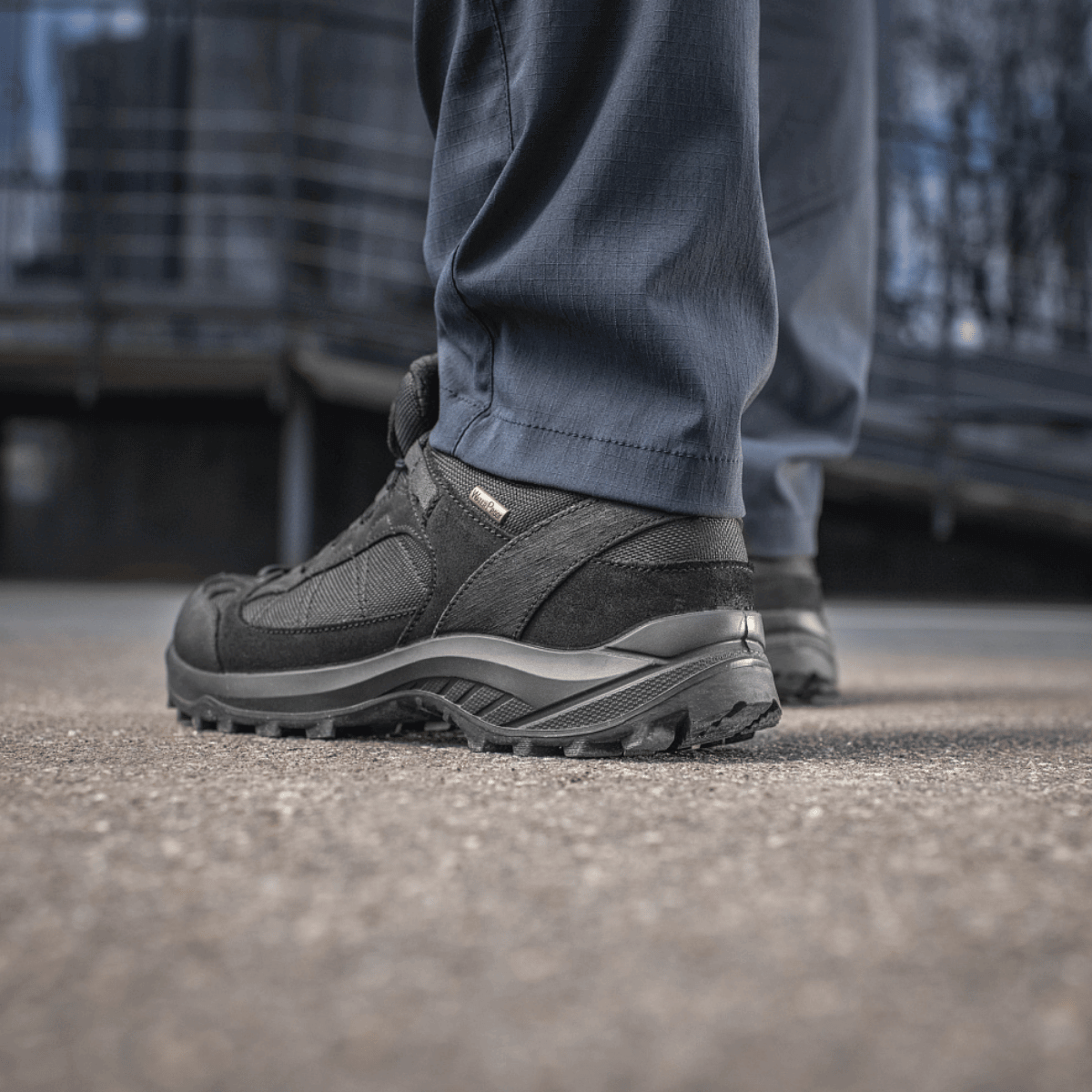 Person der bærer M-Tac Bukser Sahara Flex Light og sorte vandresko udendørs.