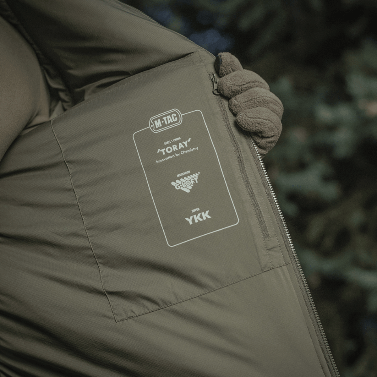 Person viser indersiden af M-Tac Paladin Jakke med Toray og YKK mærker.
