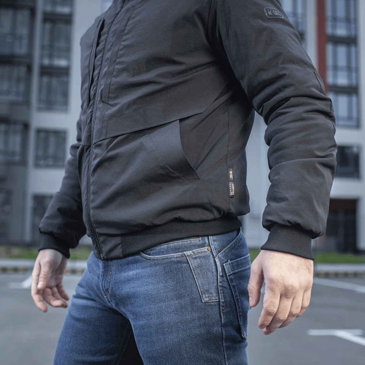 Mand iført M-Tac Rubicon Jakke Gen. II, moderne bomberjakke i slidstærkt, vandafvisende Cordura-stof, udendørs baggrunde.