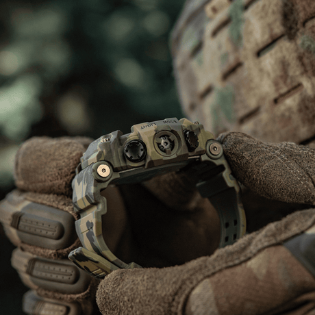 M-Tac Tactical Klocka 2037 hålls av person i handskar, utomhusmiljö, robust design för utomhus, taktisk och vardaglig användning.