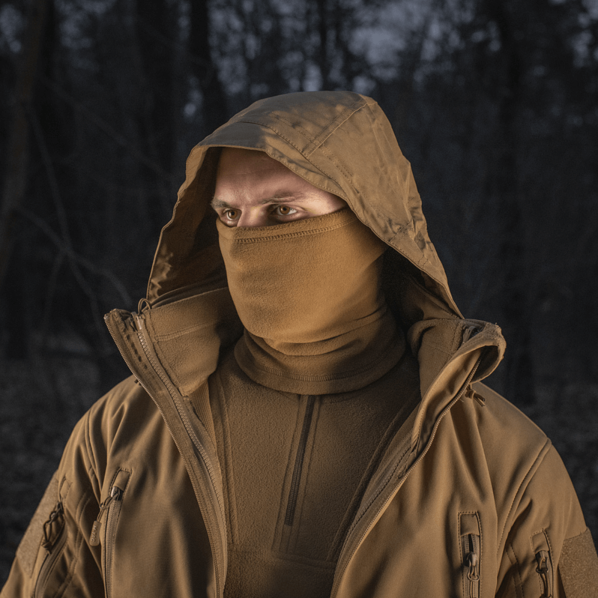 Person iført M-Tac Tube Scarf Polartec som ansigtsmaske i en skov om natten, beskyttet mod kulde og vind. Ideel til udendørs aktiviteter.