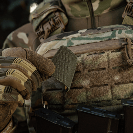 Soldat i kamouflage håller M-Tac Patch Ukraine Flag med vapensköld fäst med Velcro på utrustning.