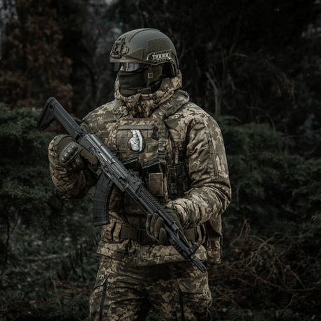 Soldat i kamouflage med gevär i skog bär M-Tac Patch M67 Granat 3D PVC på taktisk väst