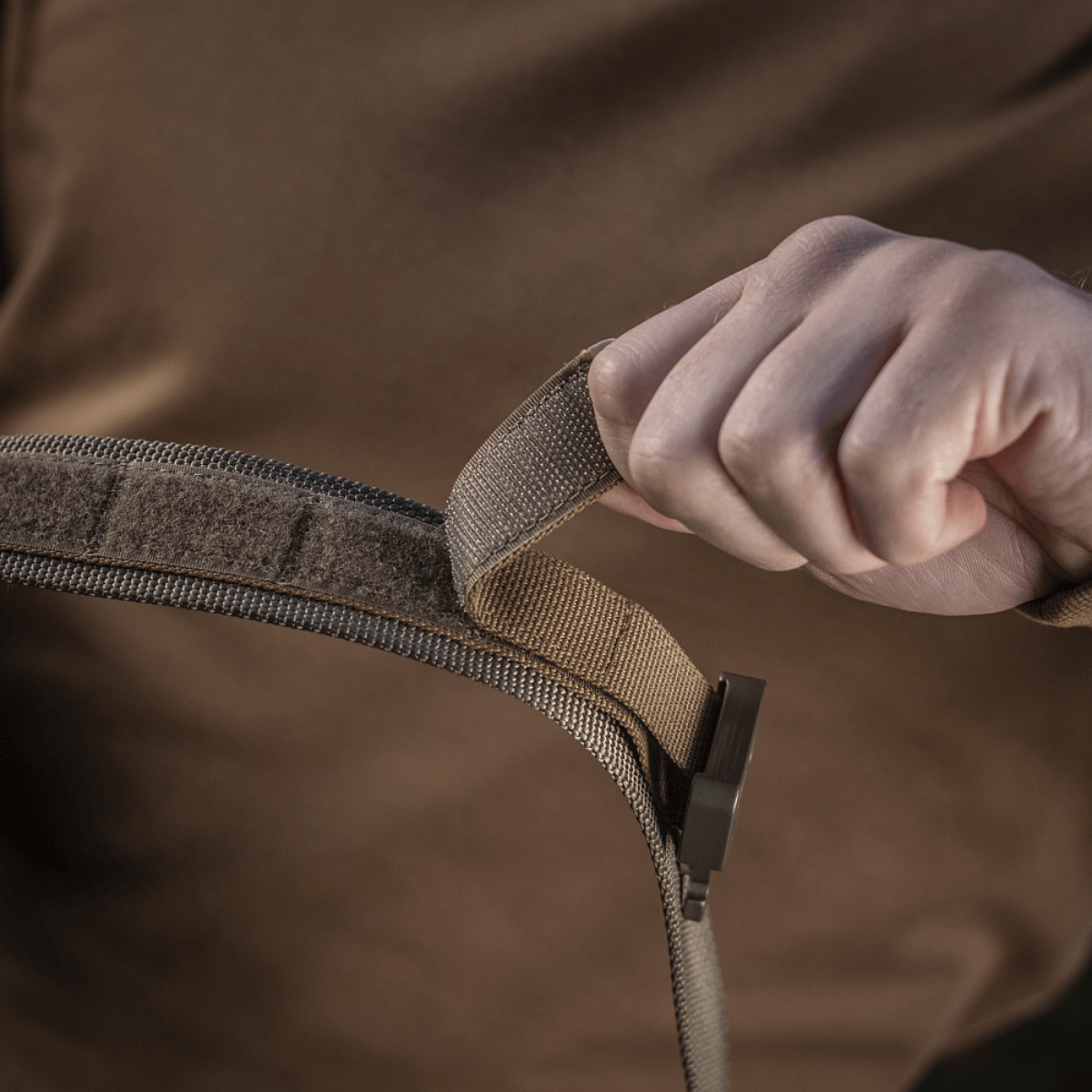 Person demonstrerer M-Tac Cobra Buckle Taktisk Bælte Laser Cut med COBRA lås og MOLLE interface