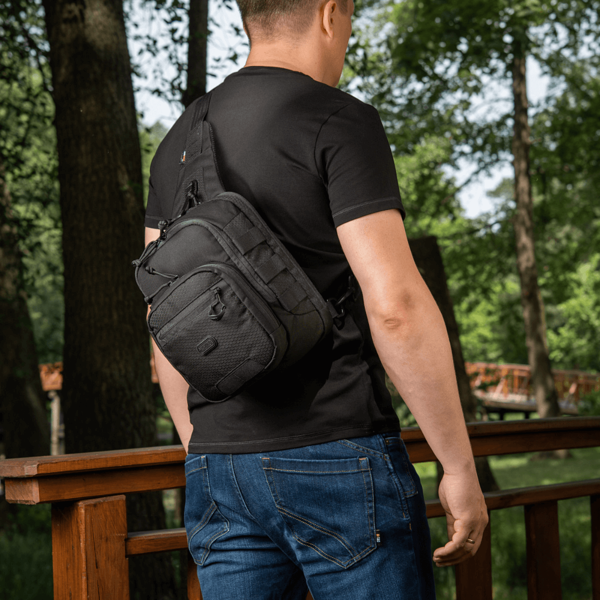M-Tac Cross Bag Elite Hex som sling pack til én skulder, holdt af en mand i sort t-shirt, perfekt til daglig og taktisk brug.