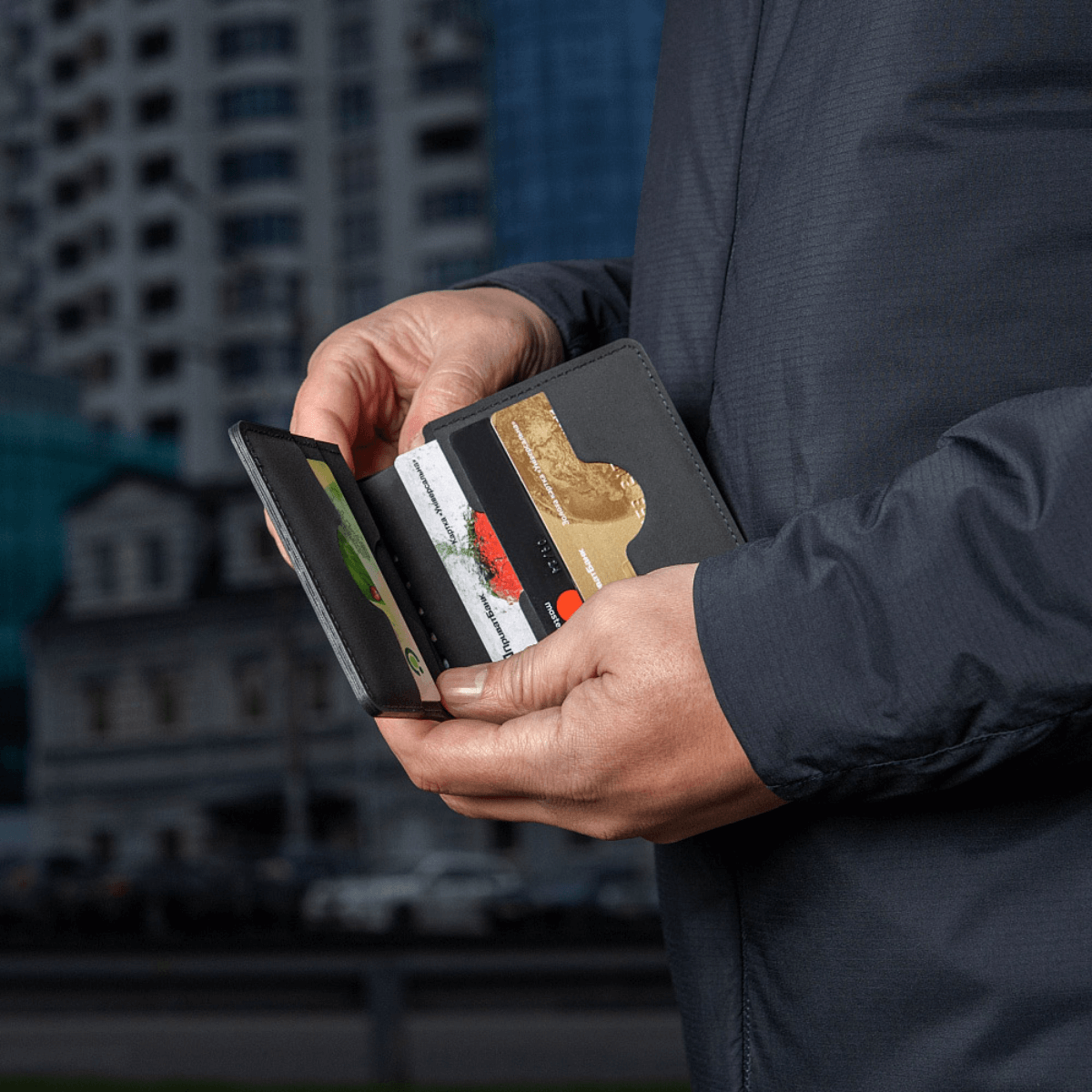 Mand holder en M‑Tac Pung Slim Elite med kort og sedler, stilfuld og kompakt pung til sikker opbevaring.