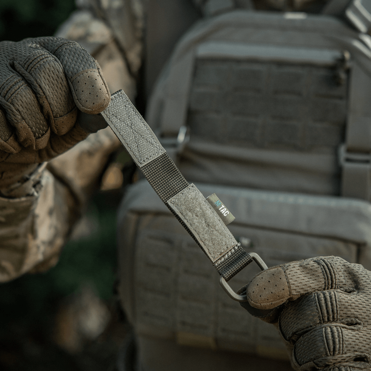 M-Tac Fastgørelse med D-ring i brug på taktisk udstyr med MOLLE-system, ideel til sikker ophængning og justerbar pasform.