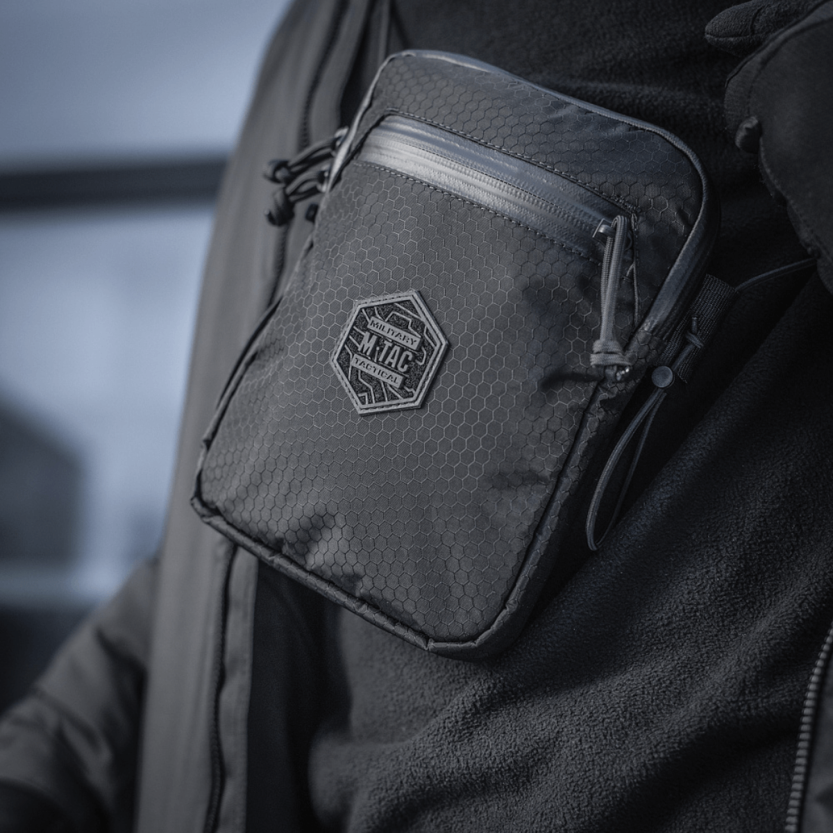 En person bærer en kompakt, robust M‑Tac Pocket Bag Elite HEX med slidstærke YKK lynlåse, ideel til hverdagens opbevaringsbehov.