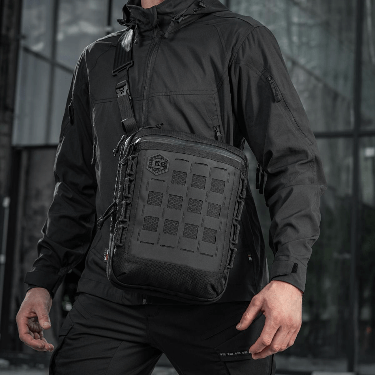 M-Tac Tablet Bag Laser Cut Hex i sort med Laser Cut MOLLE, bæret af en person, velegnet til EDC, dokumenter og tablet-opbevaring.
