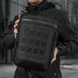 M-Tac Tablet Bag Laser Cut Hex i Cordura stof med Laser Cut MOLLE og hurtig adgang, holdt af en person i sort jakke.
