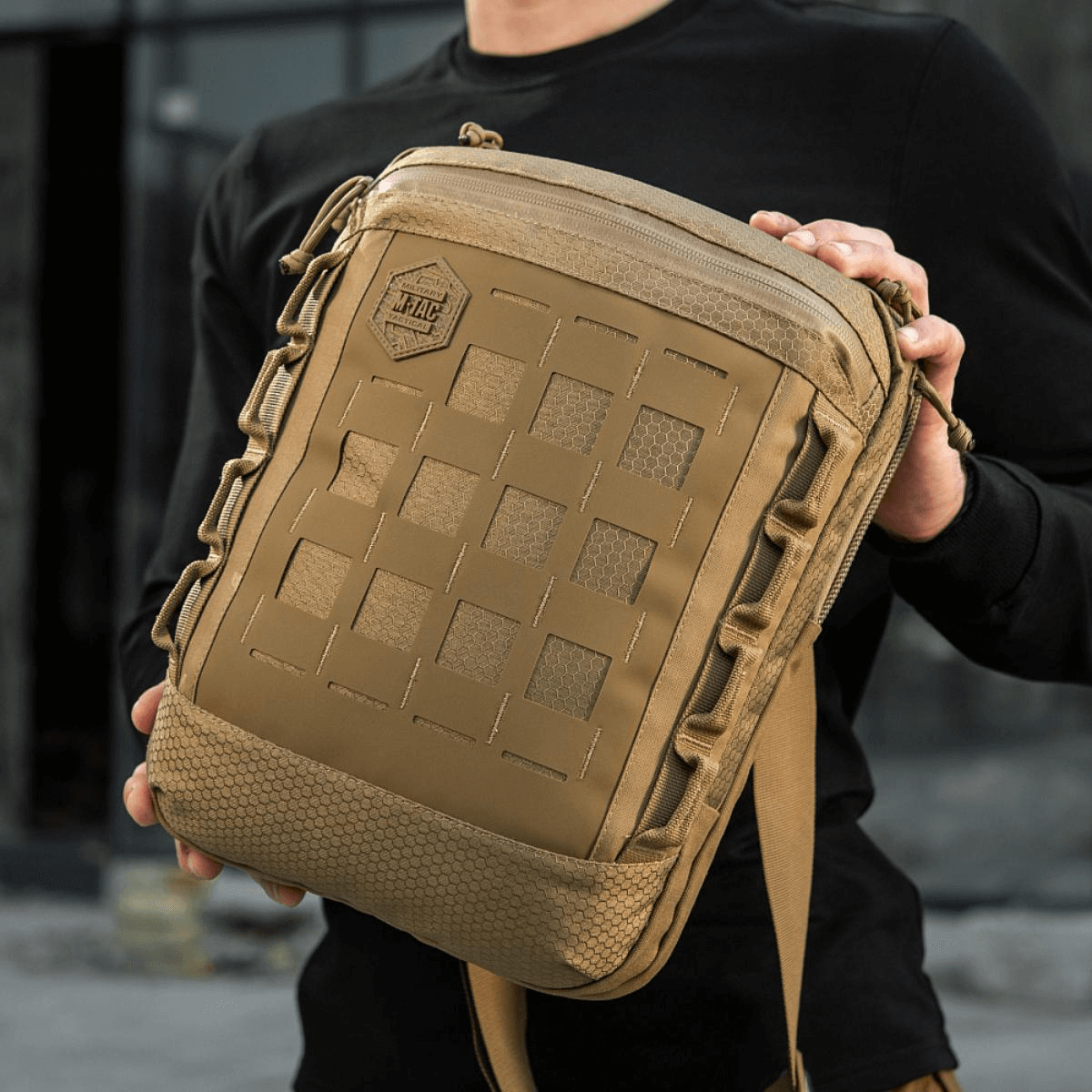 M-Tac Tablet Bag Laser Cut Hex i Cordura med Laser Cut MOLLE, holdes af en person, perfekt til EDC og tablets. Praktisk og alsidig taske.