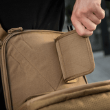 Person demonstrating the quick access feature of M-Tac Tablet Bag Laser Cut Hex in tan color with concealed compartment.