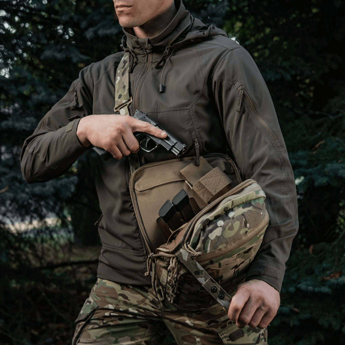 Mand med M-Tac Tablet Bag Laser Cut Hex i camouflage, viser skjult våbenopbevaring og hurtig adgang i tasken.