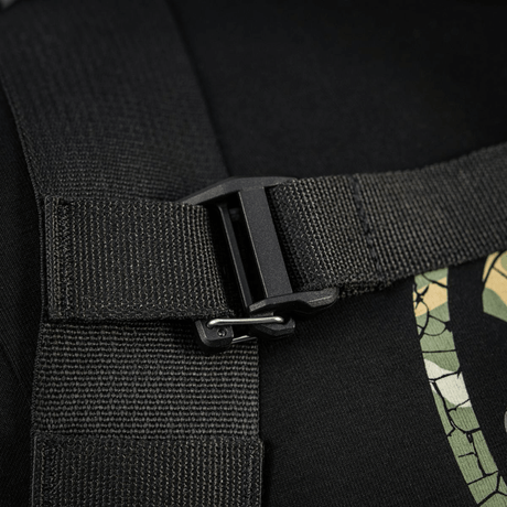 Nærbillede af sort stropspænde på rygsæk med camouflage-trykdetalje, robust konstruktion og sikker lukning.