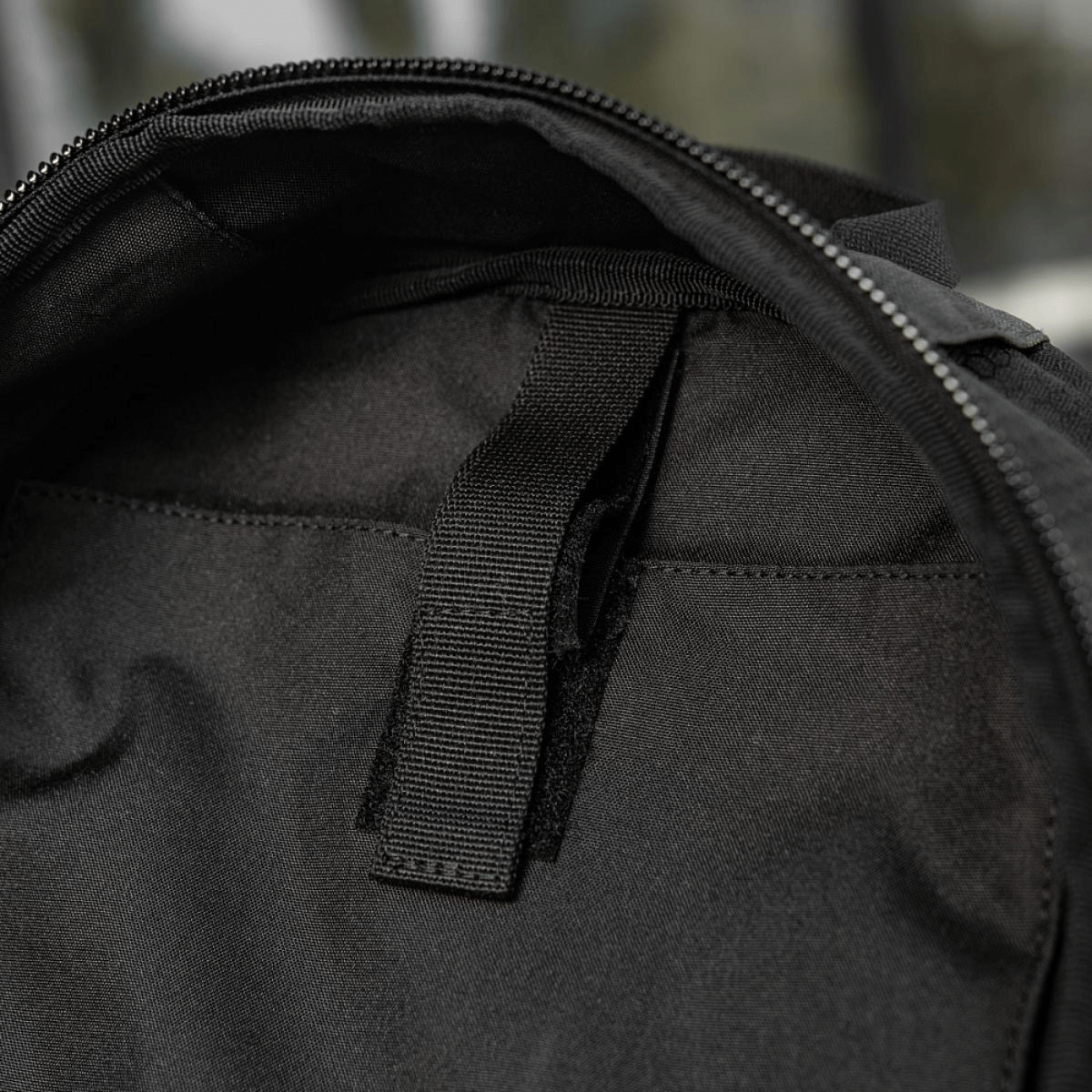 Sort taske med lynlåsdel og sort håndtag, set indefra