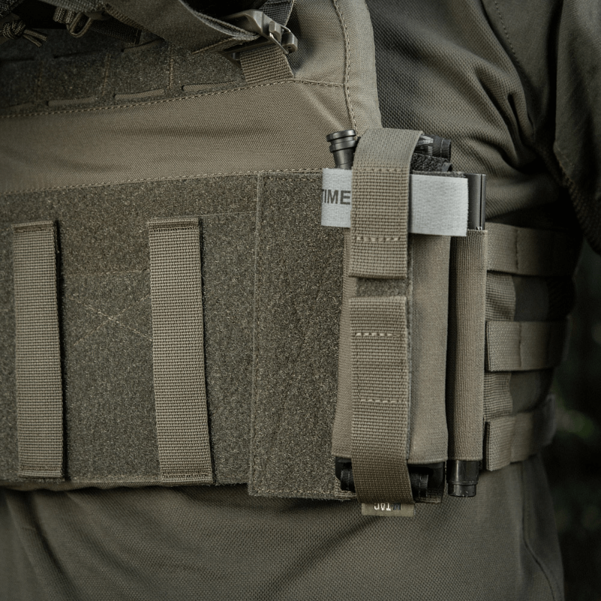 M‑Tac Tourniquet Pouch Elastic Gen.5 monteret på taktisk udstyr, viser sikker fastgørelse med elastisk bånd og velcro.