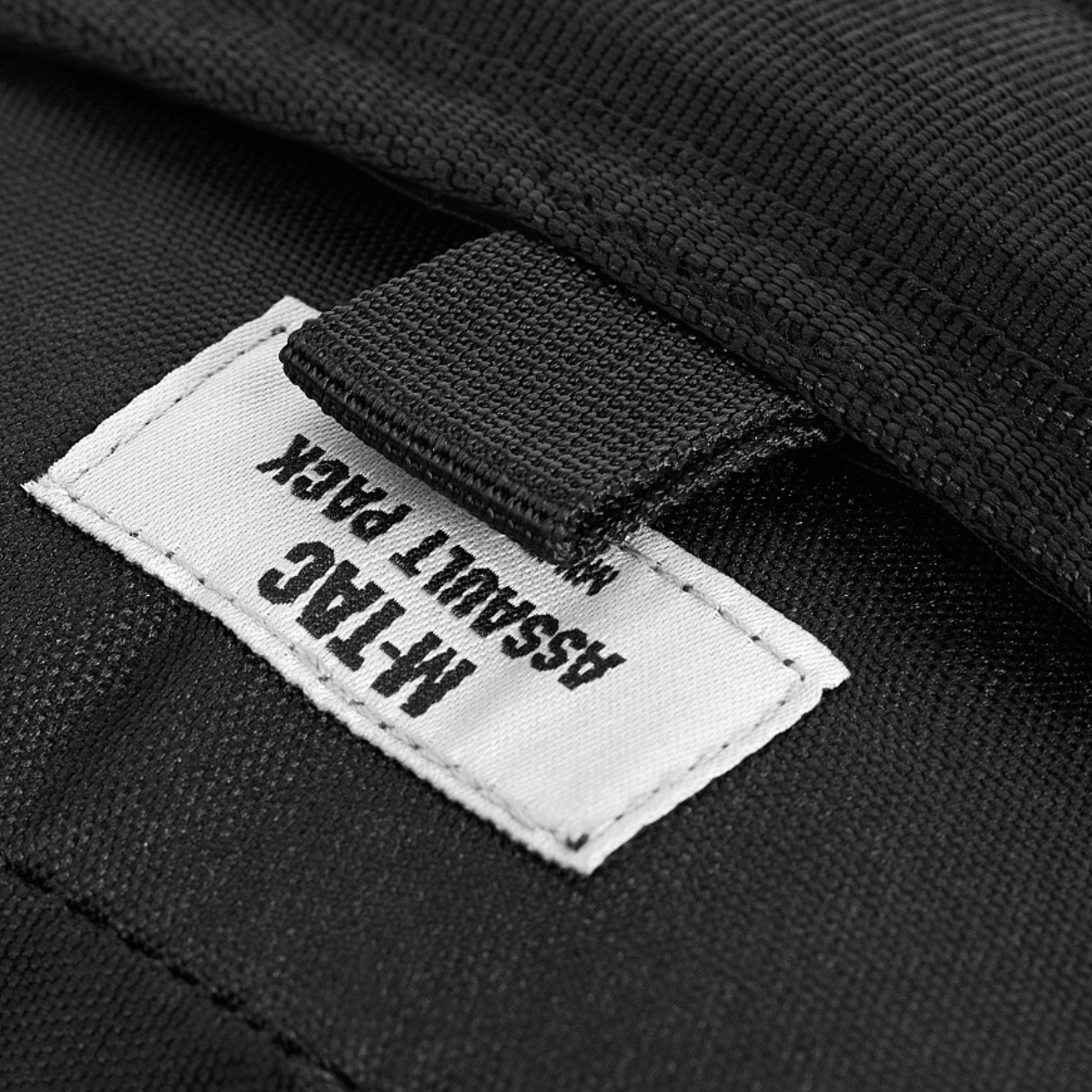 M-Tac Assault Pack Laser Cut label på en sort rygsæk med MOLLE-system, perfekt til bybrug og korte vandreture.