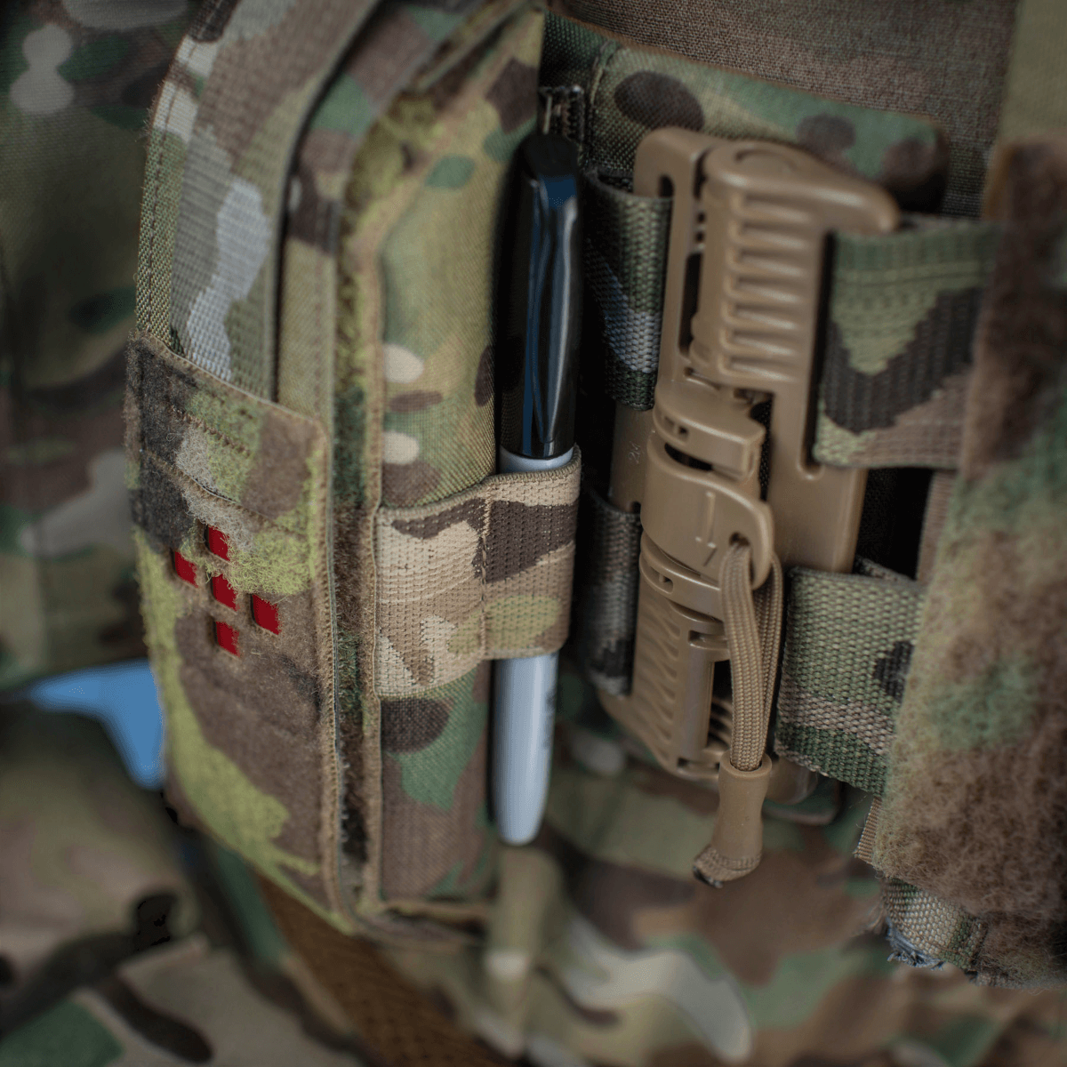 M-Tac Lomme til Tourniquet Closed i camouflage stof på uniform, holder en sort pen og medicinsk udstyr. Pålidelig beskyttelse.