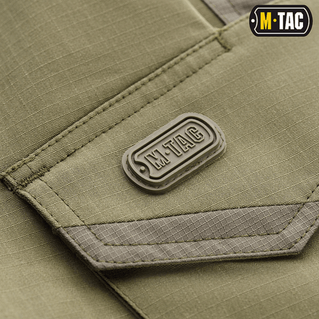 Detalje af M-Tac Shorts Aggressor Short med logo, viser taktisk designmateriale i elastisk polycotton flex rip-stop til komfort og holdbarhed.