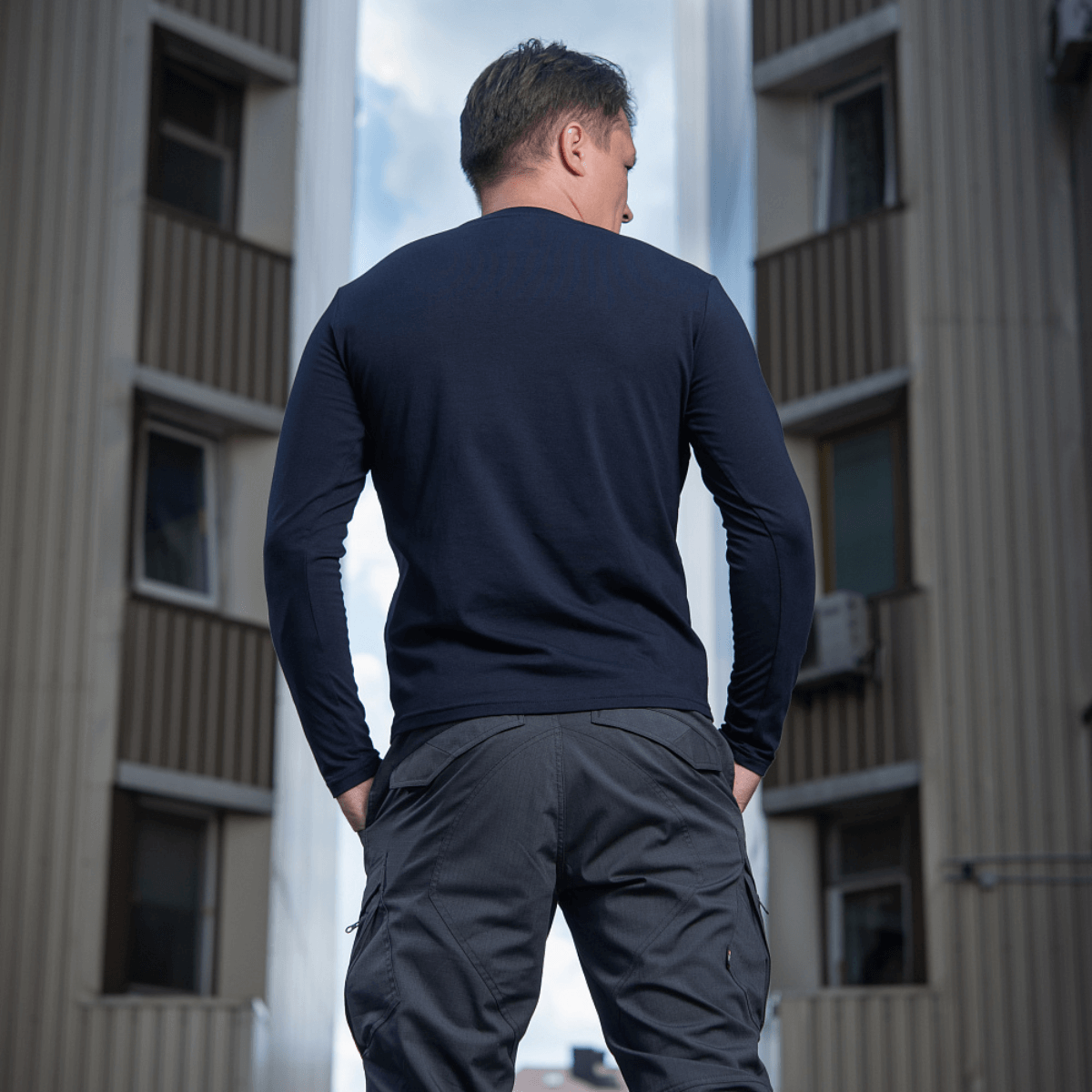 M-Tac Long-sleeve T-shirt 93/7 på en mand i bymiljø, 93% bomuld, 7% elastan, ideel til hverdag, uniform og friluftsliv