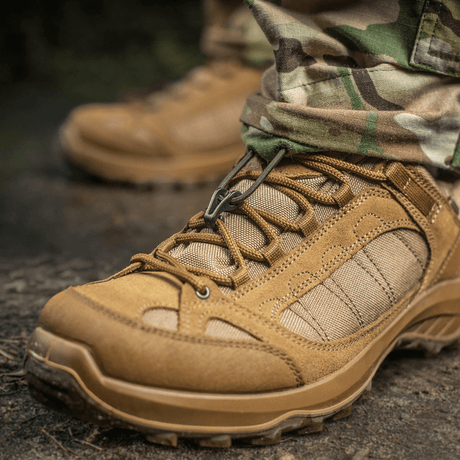 Nærbillede af taktiske støvler i læder og stof i brug på grusvej, ideelle til udendørs aktiviteter og barske forhold.