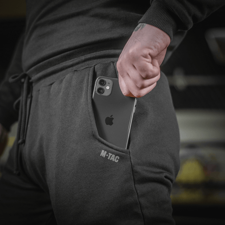 Mand iført M-Tac Bukser Cotton Classic, viser en smartphone i buksernes sidelomme, som er perfekt til sport og daglig brug.