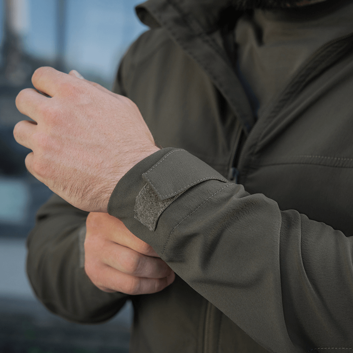 Mand justerer manchet på M-Tac Flash Jakke, viser jakke uden velcrofelter på ærmer, der er letvægts og ideel til udendørsaktiviteter.