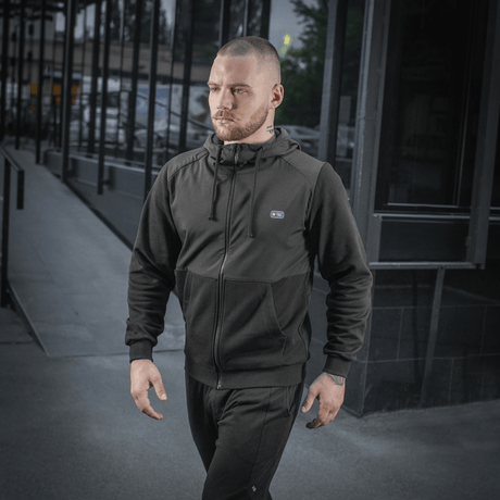 Mand iført M-Tac Pilgrim Bomberjakke, stilfuldt design med hætte, perfekt til hverdagsbrug og sport, den holdbare og komfortable jakke.