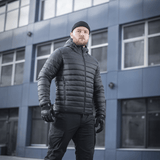 M-Tac Stalker Gen.III Jakke på model foran en moderne bygning, viser stilfuldt design og høj kvalitet til kolde temperaturer.