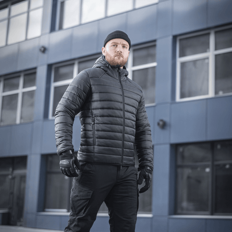 M-Tac Stalker Gen.III Jakke på model foran en moderne bygning, viser stilfuldt design og høj kvalitet til kolde temperaturer.