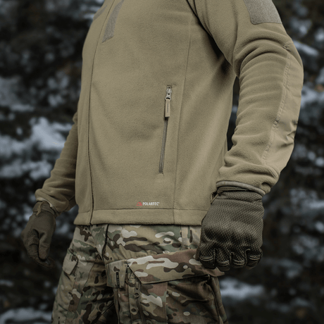 M-Tac Combat Fleece Polartec Jakke i taktisk miljø med lomme detaljer, ideel til både taktisk og casual brug.