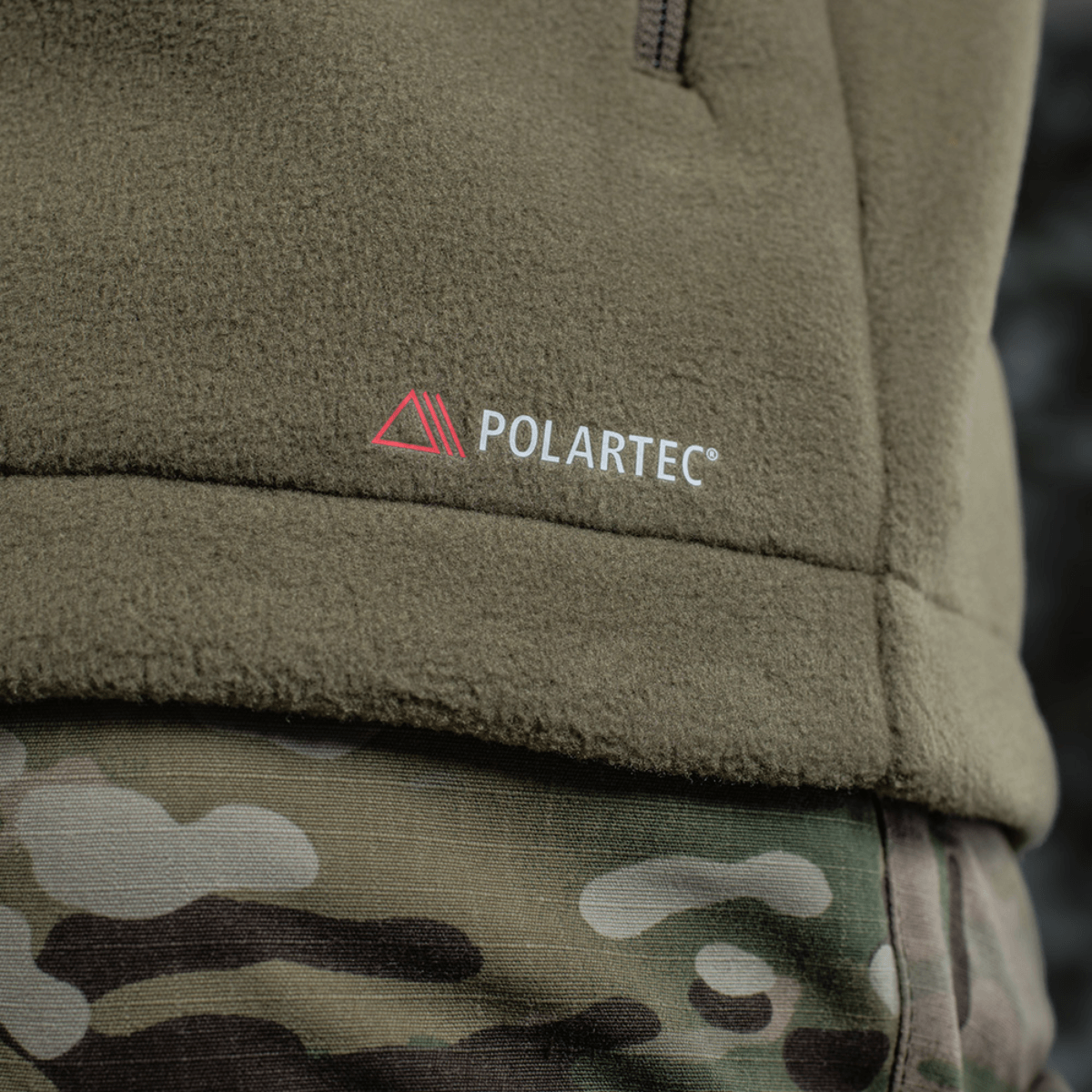 Detalje af M-Tac Combat Fleece Polartec Jakke, viser Polartec®-mærket og camo-bukser, ideel til taktisk og casual brug.